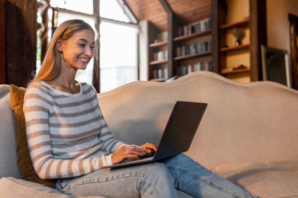 Smiling woman working on laptop at home while adding a listing to sound money